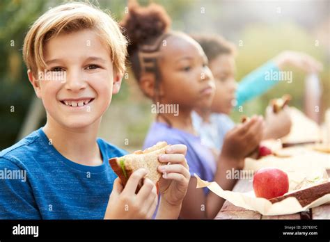 Portrait Of Boy With Friends Eating Healthy Picnic At Outdoor Table In Countryside Stock Photo ...