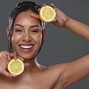Face, skincare and woman with lemons for beauty in studio isolated on gray background. Portrait ...