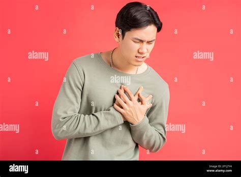 A photo of a handsome Asian man holding his arms around his chest because of a heart attack ...