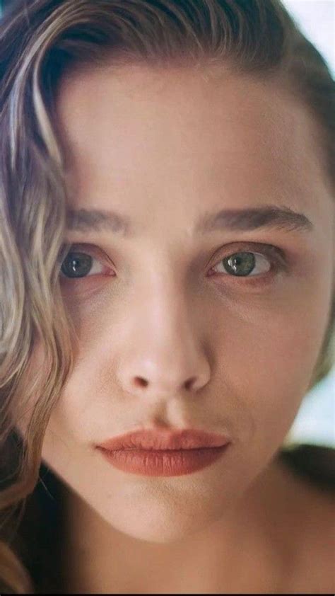 a close up of a woman with blue eyes and wavy hair looking at the camera