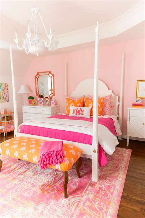 a pink and orange bedroom with white bedding, chandelier, dressers and mirror