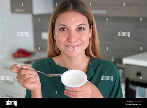 Attractive woman holds bowl of Greek yogurt in her hand and smiles at camera indoors Stock Photo ...