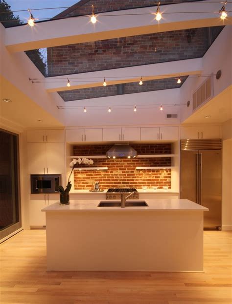 a kitchen with an island and skylight above it is lit by recessed lights