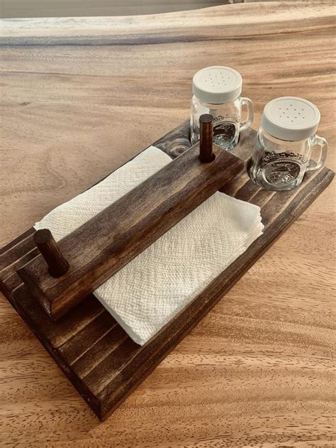 two salt and pepper shakers sitting on top of a wooden tray with napkins