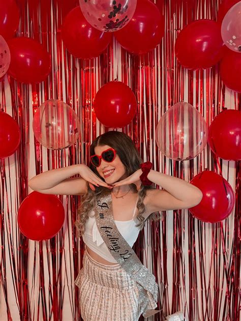 a woman posing in front of balloons and streamers with her hands behind ...