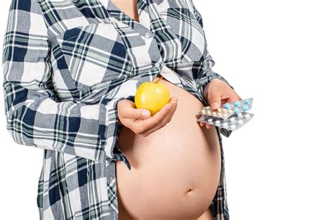 A pregnant woman holds an apple in one hand and medicines in the other - Creative Commons Bilder