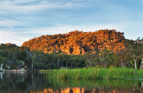 a lake surrounded by trees and grass with the sun shining on it's side