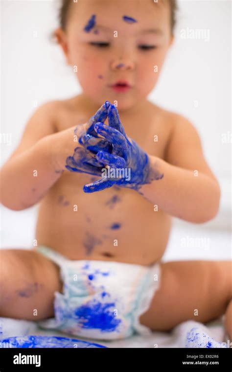 Baby girl dabbling with finger paints in white kitchen Stock Photo - Alamy