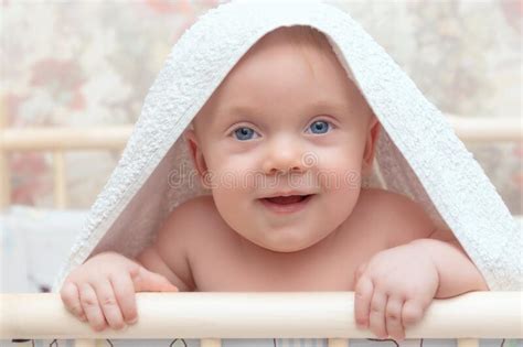 A Child with Large Blue Eyes Looks into the Camera Under a White Towel ...