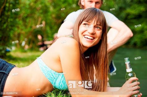 Couple relaxing in park, young woman holding glass bottle, Stock Photo, Picture And Royalty Free ...