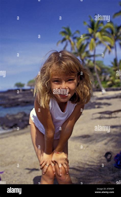 A cute smiling young girl strikes a pose on a beach at the Kona Village ...