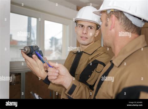 apprentice builder with electric drill Stock Photo - Alamy