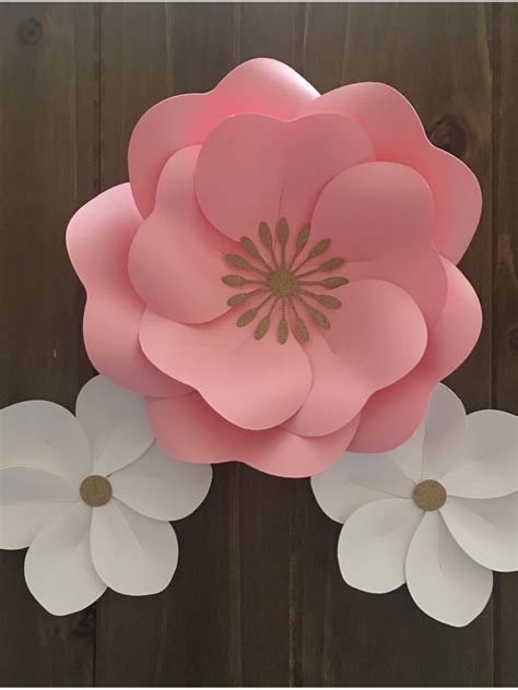 paper flowers are arranged on a wooden surface, with one large pink ...