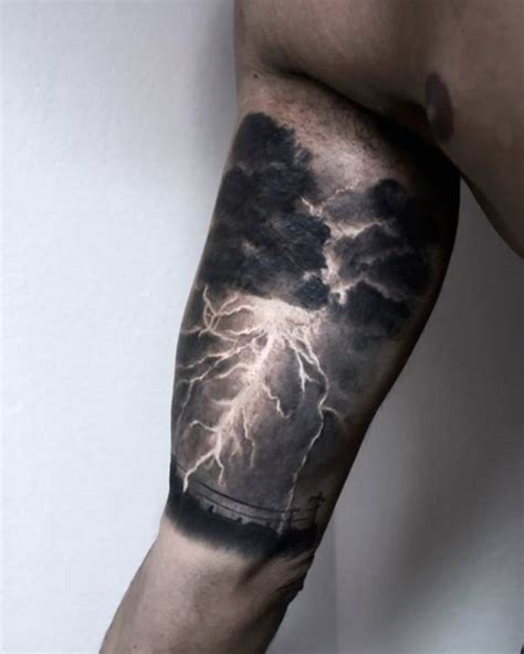 a man's arm with lightning and clouds tattoo on the left side of his arm