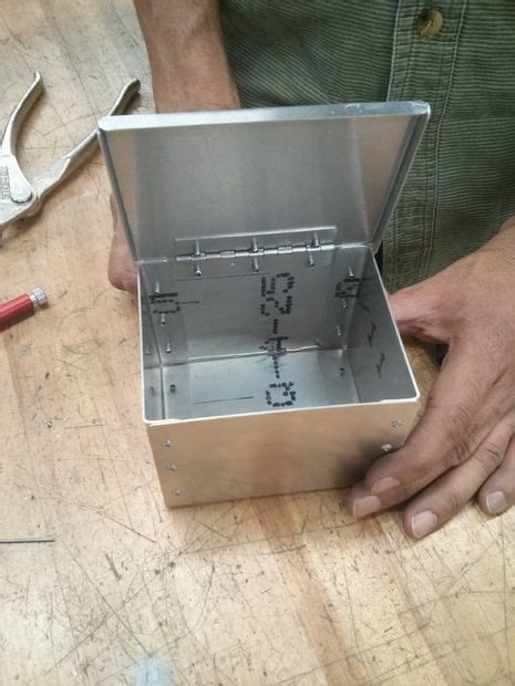 a man is holding an open box on a wooden table next to tools and other ...