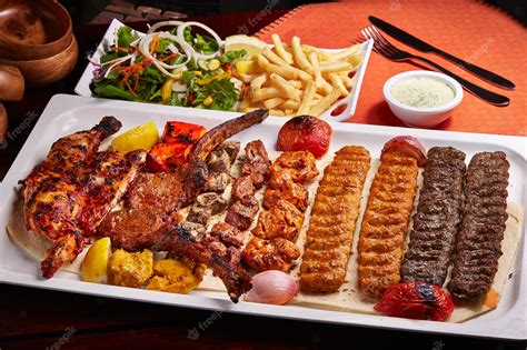 Premium Photo | Spicy bbq Mixed Grills platter with tikka boti kababs fries salad and raita ...