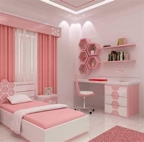 a pink and white bedroom with shelving units on the wall, desk and bed
