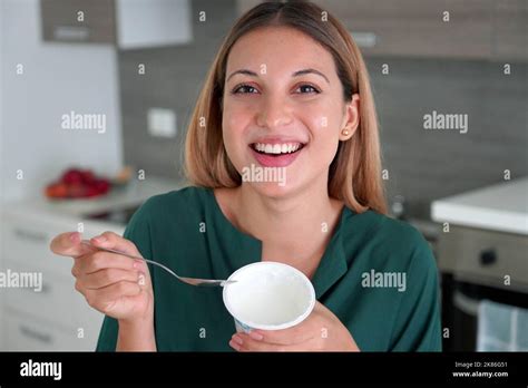 Beautiful girl holds bowl on Greek yogurt in her hand and smiles at camera indoors Stock Photo ...