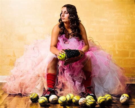 a woman in a pink dress sitting on top of a wooden floor with soccer balls
