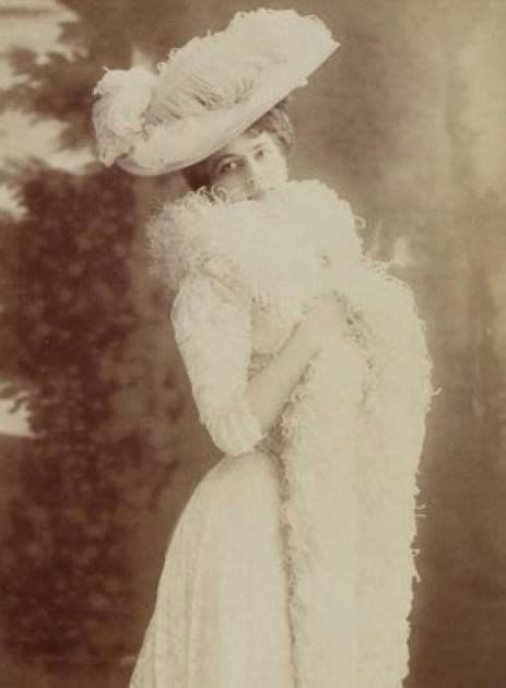 an old fashion photo of a woman wearing a white dress and large feathered hat