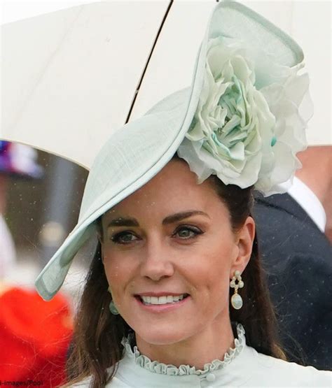 a woman wearing a white hat with a flower on it and an umbrella over her head