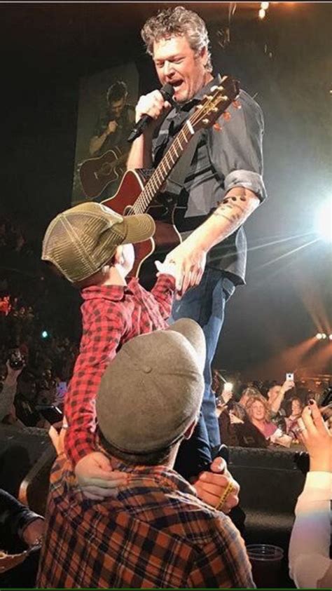 a man on top of another man holding a guitar in front of an audience at a concert