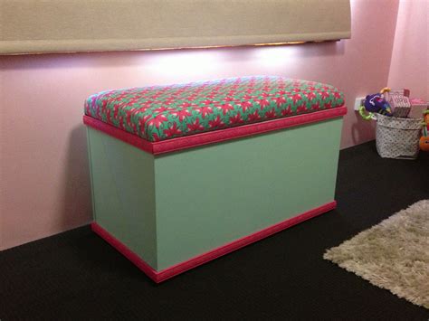 a pink and green storage box sitting on top of a black floor next to a ...