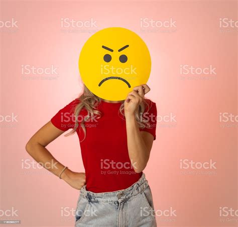 Attractive Young Woman Holding An Angry Face Emoji Emoticon Symbol Isolated On White Background ...