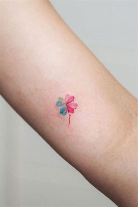 a small four - leaf clover tattoo on the left arm and right arm, it is pink with green leaves