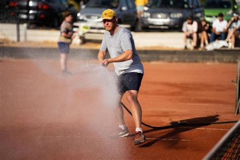 Premium Photo | Friends playing tennis on a clay court watering and bagging a clay court doing ...