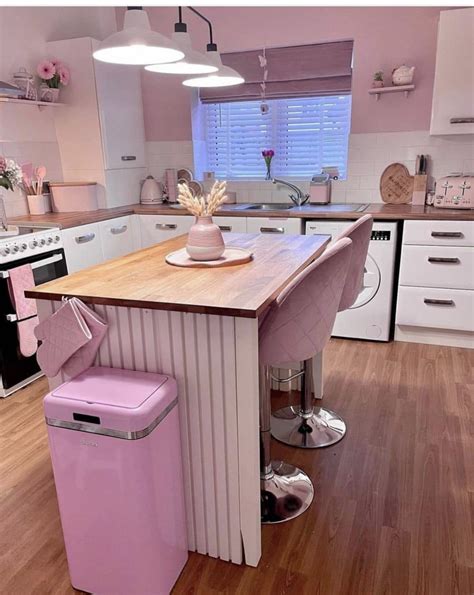 a pink kitchen island in the middle of a wooden floor