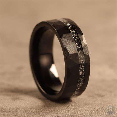a black ring with an intricate design on the outside and inside, sitting on a surface
