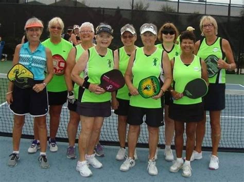 a group of women standing on top of a tennis court holding racquets