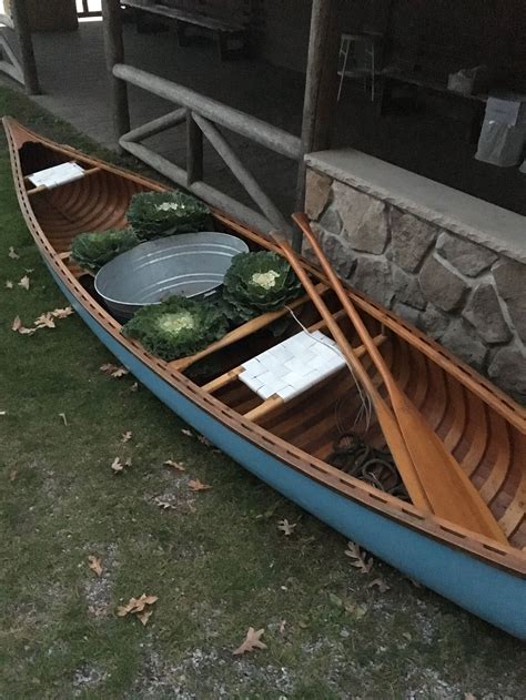 A classic restored wooden canoe holds an aluminum tub ready for ice/drinks, flanked by cabbage ...