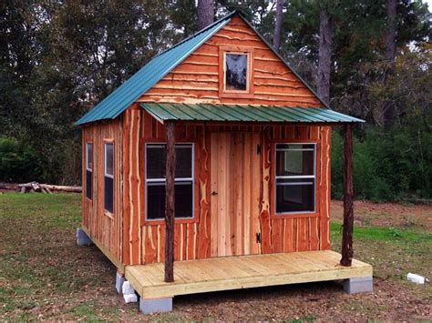 a small wooden cabin sitting in the middle of a field with trees and ...