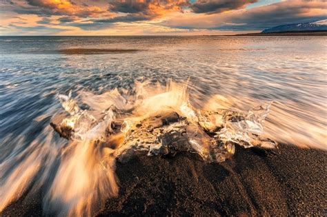 Premium Photo | Wave crashing iceberg melting on black sand beach in ...