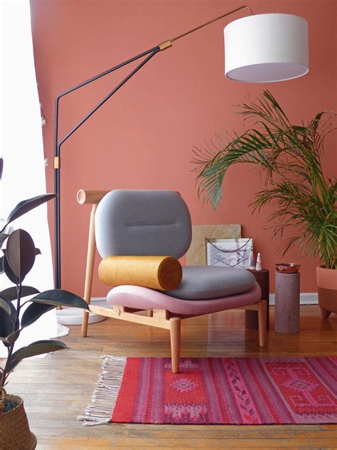a living room with pink walls and wooden flooring, potted plants on the far wall