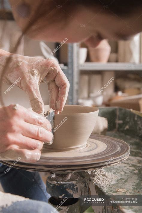 Close up of a woman shaping pottery clay on a pottery wheel in a ceramic workshop. — female ...