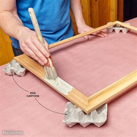 a man is using a brush to paint the edges of a wooden frame with tape