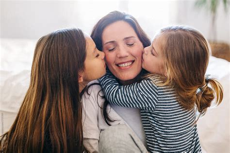 "Portrait Of Daughters Kissing Her Mom At Home." by Stocksy Contributor "BONNINSTUDIO " - Stocksy