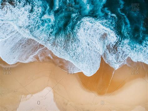 Blue ocean waves aerial drone shot on sandy beach stock photo - OFFSET