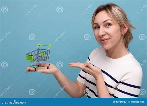 Young Mother Showing a Shopping Trolley on a Blue Background with Copy ...