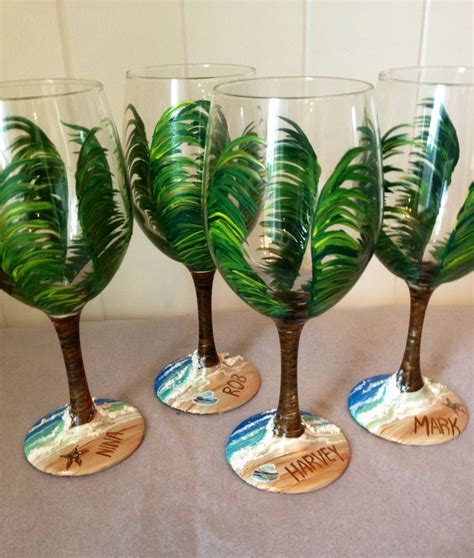 four wine glasses with palm trees painted on them