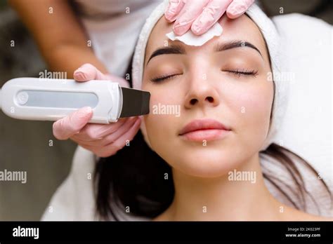 Facial cleansing with ultrasound scrubber. Woman receiving ultrasound facial peeling and ...