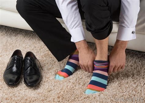 man-putting-on-colorful-socks-on-carpet