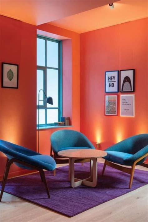 an orange room with two blue chairs and a round table