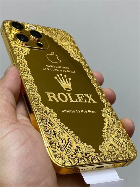 a hand holding a gold iphone case with the rolex logo on it