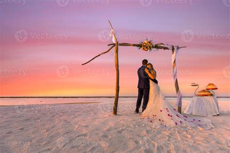 The bride and groom under wedding arch on beach. Romantic wedding ...