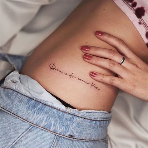 "Dreams do come true" lettering tattoo on the hip