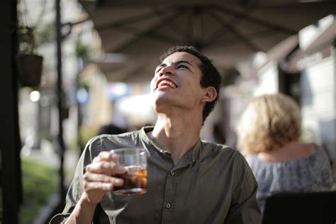 Happy ethnic man having drink with ice cubes in street cafe in sunny hot day · Free Stock Photo